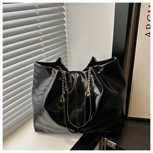 Detail of high-shine black tote bag with gold chain strap and spacious interior