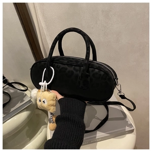 Close-up of black leopard embossed baguette bag with cute plush cube pendant accessory