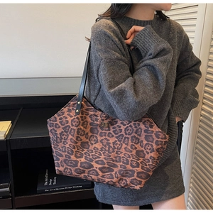 Close-up of leopard print tote bag featuring a gold twist-lock closure and slim black straps
