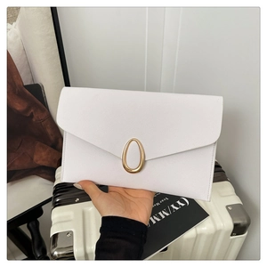 Detail of white envelope clutch featuring textured leather and a gold oval metal clasp
