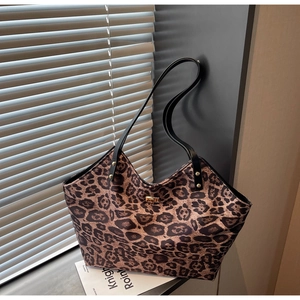 Close-up of leopard print tote bag with gold metal twist lock and durable black shoulder straps