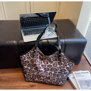 Close-up of leopard print tote bag with black leather straps and gold metal logo