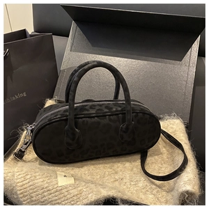 Detailed view of black leopard print suede baguette bag with silver hardware and strap