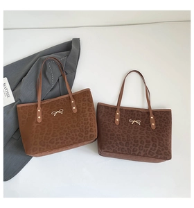 Detail of leopard print tote bag with plush fabric and golden bow hardware accents