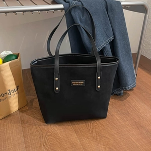 Minimalist large black suede tote bag with golden rivets and dual handles for daily commute