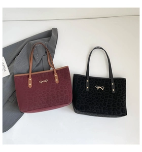 Detail of leopard print tote bags in burgundy and black with gold bow metal buckles