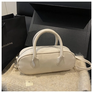Macro detail of cream white faux leather cylinder handbag with silver zipper and dual handles