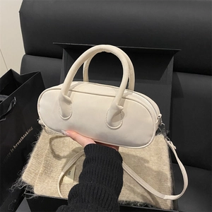 Minimalist beige suede leather cylinder shoulder bag with top handle and adjustable strap