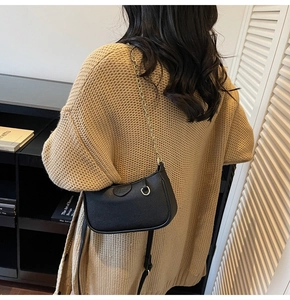 Close-up of black lychee leather crescent bag with gold chain strap on a model