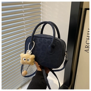 Detail of navy blue leopard embossed crossbody bag with a cute plush bear charm pendant