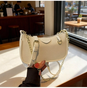Detail of off-white leather crossbody bag with strawberry pendant and gold chain