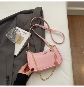 Detail view of pink lychee leather bag with gold chain and cute strawberry pendant strap