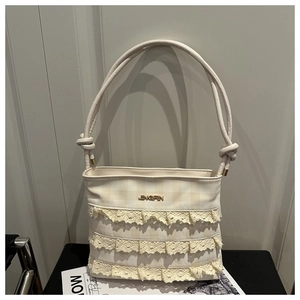 Close-up of beige lace shoulder bag with textured plaid fabric and knotted strap detail