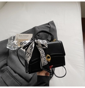 Dettaglio borsa a trapezio nera in ecopelle con foulard a cuori e chiusura dorata