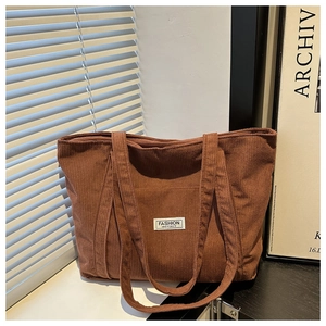 Close-up of brown corduroy tote bag with front pocket and white fashion instinct label