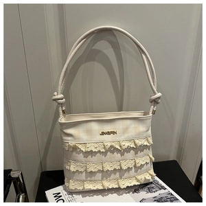 Close-up of beige plaid tote bag featuring tiered lace ruffles and gold metal logo