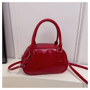 Dettaglio borsa baguette rossa lucida in pelle PU con cerniere argento e doppi manici