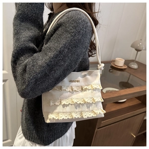 Detailed close-up of ivory canvas bucket bag with elegant triple-layer lace ruffles