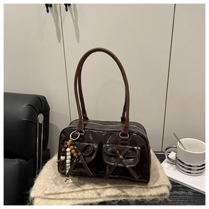 Detail of dark brown glossy Boston bag with twin bow pockets and wooden bead charm