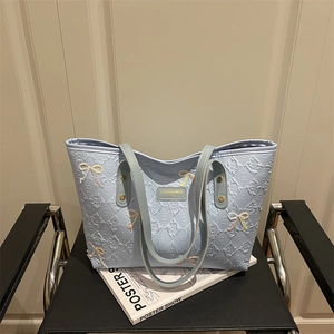 Light blue quilted tote bag with embroidered bows and dual shoulder straps on a chair