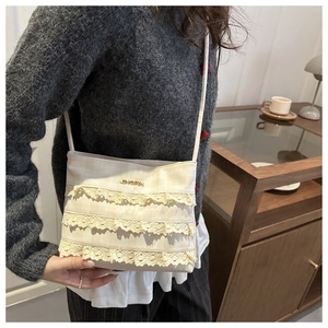 Close-up of cream lace tote bag with tiered ruffles and golden brand detail on fabric