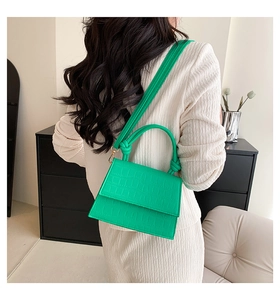 Detail of green crocodile pattern crossbody bag with a unique knot handle design