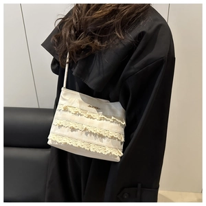 Detailed close-up of layered yellow lace ruffles on a creamy white tote bag underarm style