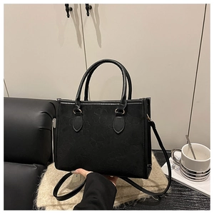 Détail du sac cabas noir avec motifs trèfles embossés et doubles poignées