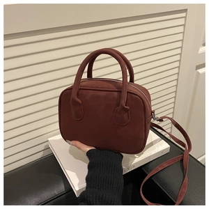 Détail du sac à main rouge foncé en similicuir avec poignées cylindriques et fermeture argentée