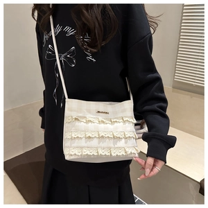 Close-up of ivory lace crossbody bag with three-tier ruffles and golden metal logo