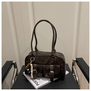 Macro view of dark brown patent leather shoulder bag featuring silver buckle front pockets