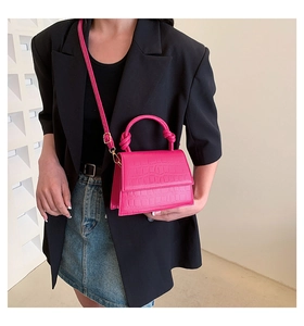Detail of fuchsia crocodile embossed mini bag with knotted handle and shoulder strap