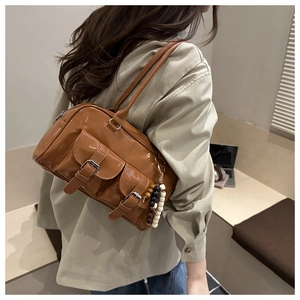 Brown faux leather Boston bag with pocket details and beads shown in side view