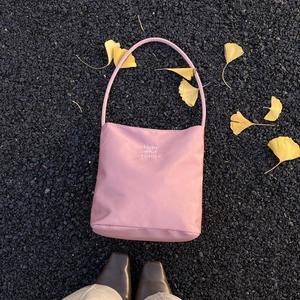 Pink nylon bucket shoulder bag with Hope and Future embroidery on asphalt background