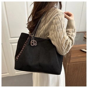 Side view of a black suede tote bag with brown woven rope and round ornament detail
