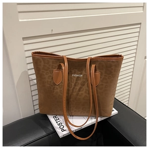 Detail of leopard print tote bag with brown handles and fashion text on a leather surface