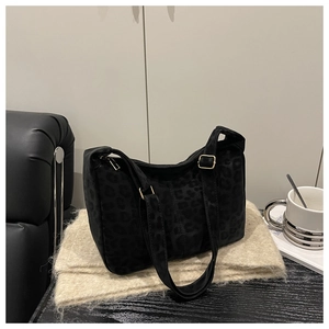Detail of black leopard embossed faux suede crossbody bag with gold buckle on a knit scarf
