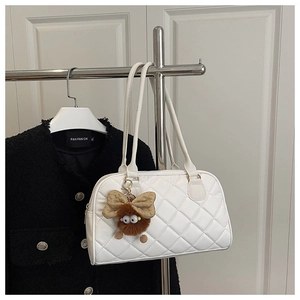 Detail of white quilted bowling bag featuring a cute brown plush monster charm accessory