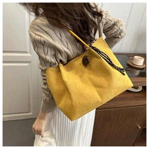 Detail of a large yellow faux suede tote bag with stylish scarf and ring charm accessory