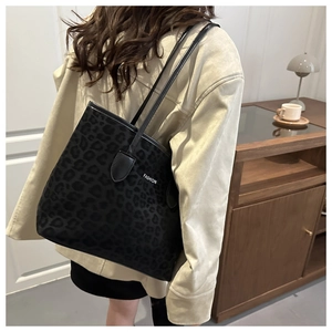 Detail of black leopard print tote bag with white FASHION print and slim straps