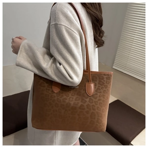 Close-up of leopard print tote bag with silver FASHION lettering and leather straps