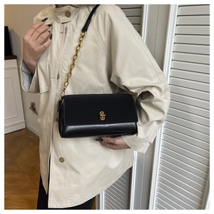 Close-up of black leather crossbody bag with gold chain strap and geometric metal lock