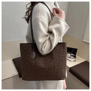 Detail of dark brown leopard print tote bag with metallic fashion logo on PU leather