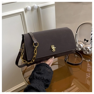 Détail d'un sac à main en daim marron avec chaîne dorée et fermoir rotatif rectangulaire