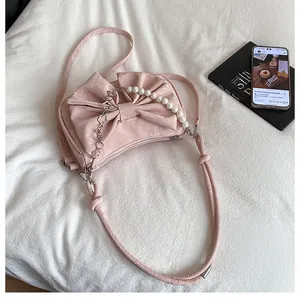 Dettaglio borsa pieghettata rosa con fiocco grande e catena in perle e fiori