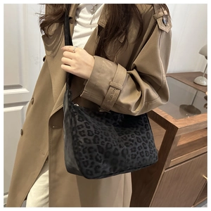 Close-up of leopard print shoulder bag worn with a khaki coat in a lifestyle setting