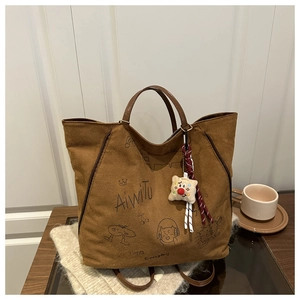 Détail du sac cabas marron en daim avec illustrations graffiti et poignées en cuir