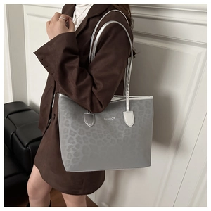 Detail of grey leopard print tote bag with FASHION logo worn by a model on shoulder