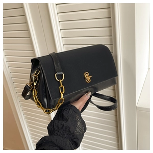 Close-up of black glossy leather crossbody bag featuring gold twist lock and chain detail