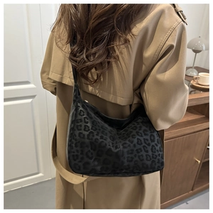 Detail of leopard print crossbody bag on model wearing a camel trench coat